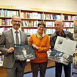 Drei Personen in einem Buchladen mit Kalendern in der Hand